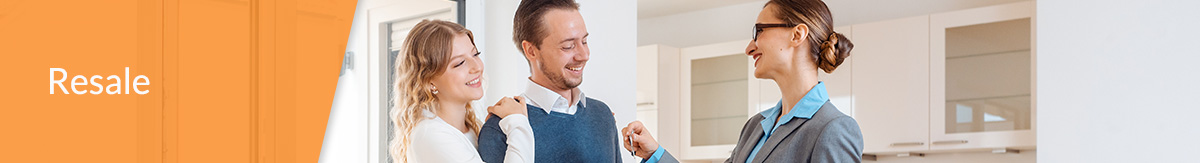 Realtor handing keys to a young professional couple inside of an empty new home.