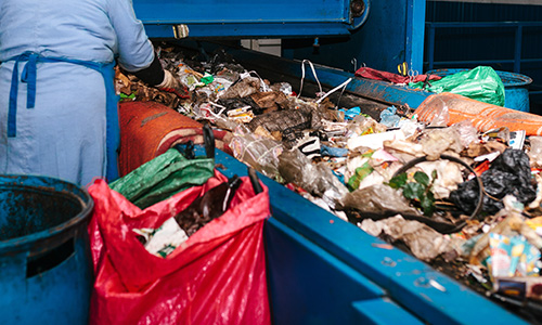 A worker removes non-recyclable items from a conveyor belt at a recycling plant.