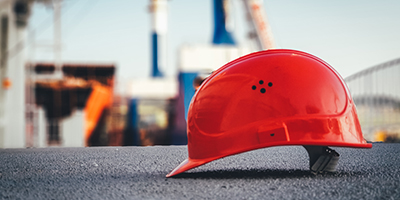 A red construction hard hat on the ground on a construction site.