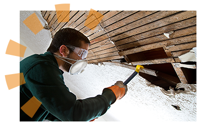 A man removing lath from a ceiling with a crowbar. 