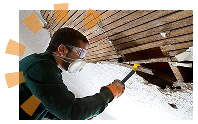 A man removing lath from a ceiling with a crowbar.