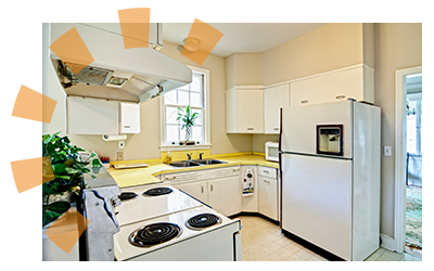 A white kitchen with dated cabinets, flooring and appliances.