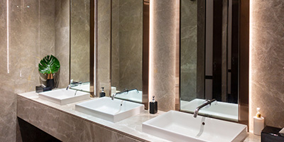 A marble bathroom counter with three ceramic sinks and mirrors.