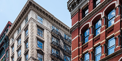 The exteriors of two renovated historic white and red brick buildings. 