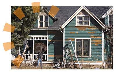 A blue home getting restored with new paint and exterior reparis by workers. 