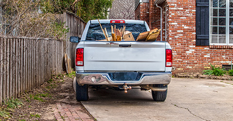 A pickup truck filled with scrap wood sitting in front of a home