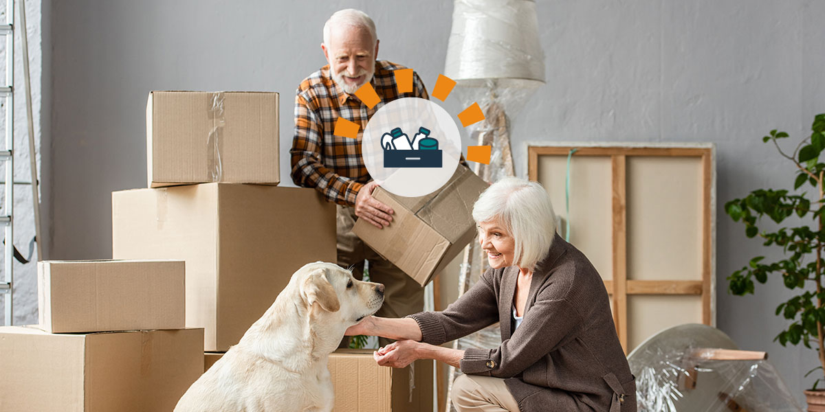 Senior couple Swedish death cleaning surrounded by cardboard boxes and their dog.