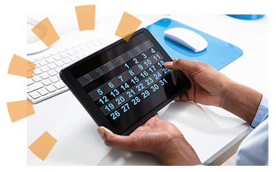 A man in a blue shirt looking at a tablet calendar at a desk