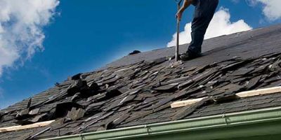 Worker Tearing Shingles Off of a Residential Building.