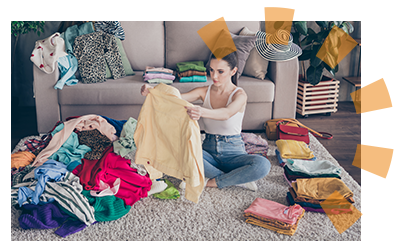 A woman sitting in a living room sorting clothing into piles. 