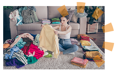 A woman sitting in a living room sorting clothing into piles.