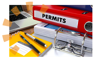 A stack of binders and notebooks on a desk with a permit sticker on the side of a red binder.