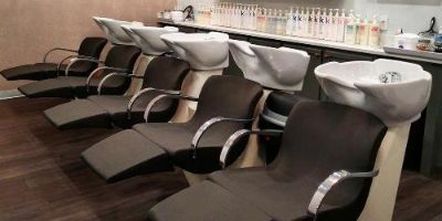 5 matching hair washing stations with black chairs and white sinks and organized products on the counter in the background