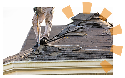 A person dressed in safety gear removing the shingles of a roof