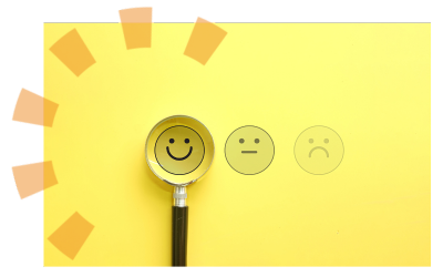 A magnifying glass hovered over a smiley face, next to a frowning face and an indifferent face.