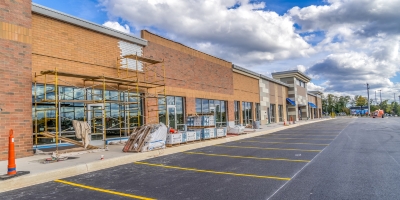 The exterior of a strip mall under construction below a partly cloudy sky.