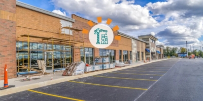 The exterior of a strip mall under construction below a partly cloudy sky.