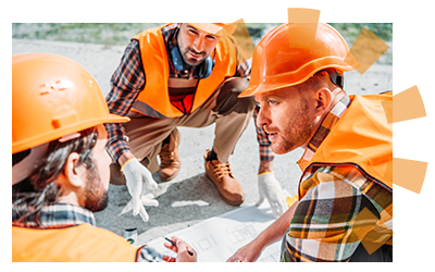 Three construction workers wearing orange hard hats looking at construction plans.