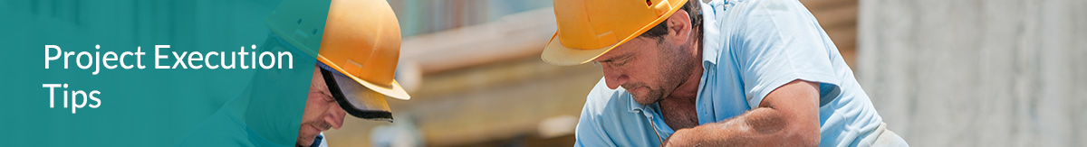 Two construction workers wearing yellow hard hats installing concrete work frames.