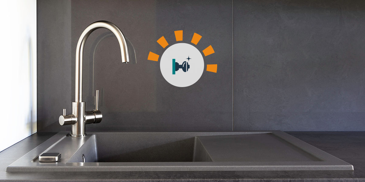 A brushed nickel kitchen faucet with black countertops.