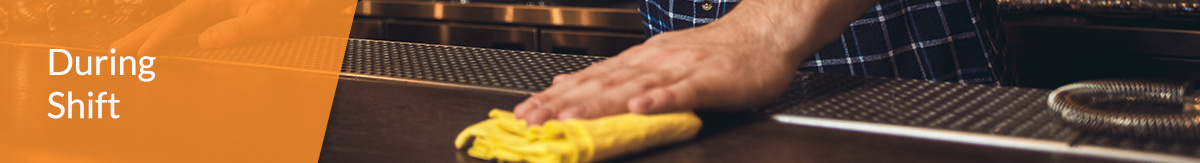 A bartender wipes down the bar with a yellow towel.