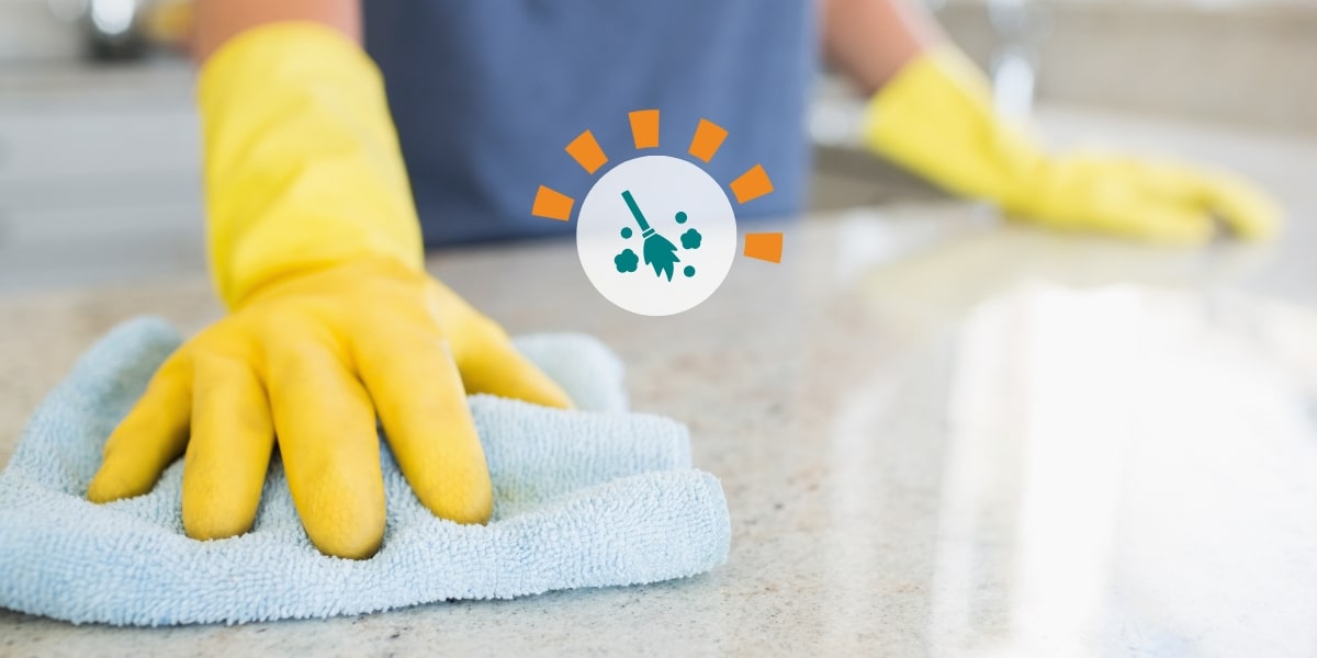 A woman with yellow gloves cleaning a countertop.