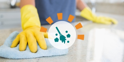 A woman with yellow gloves cleaning a countertop.