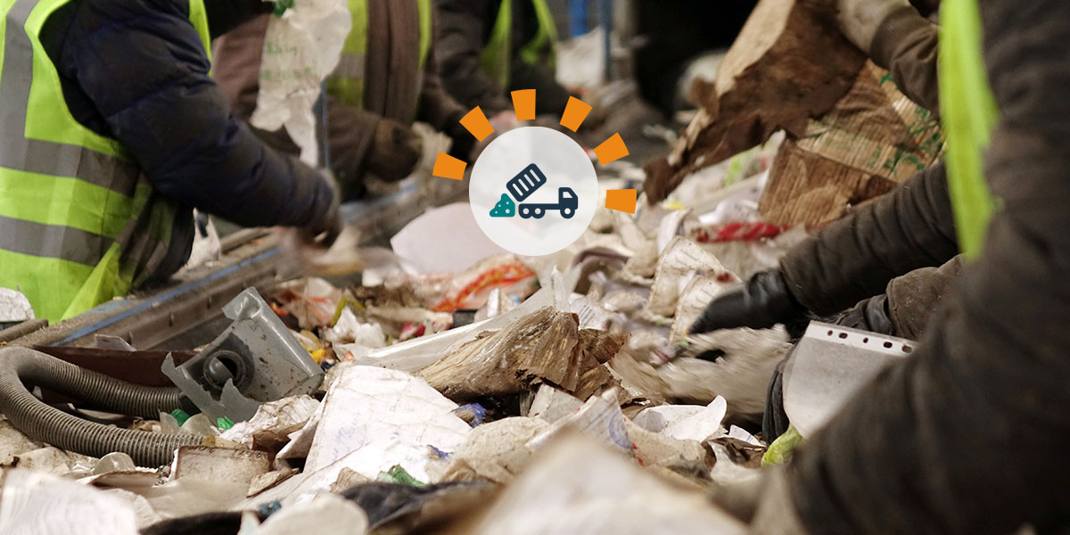 Workers sorting through trash on a conveyor belt. 