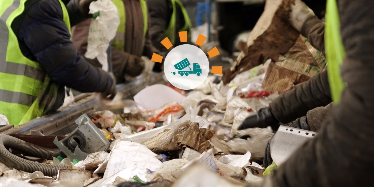 Workers sorting through trash on a conveyor belt.