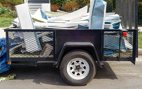Dump trailer filled with debris sitting in front of a house