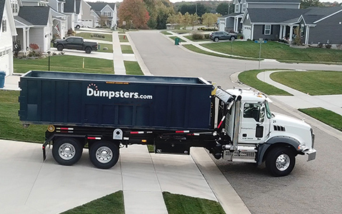 Dumpsters.com roll off truck and dumpster in a residential driveway