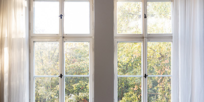 White wood windows framed by white walls and curtains.