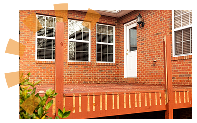 Red deck siding exposed with removed railings next to a brick home.