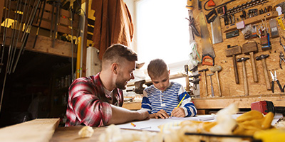 A dad helps his son with a design project at the garage workbench.