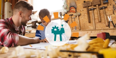 A dad helps his son with a design project at the garage workbench.