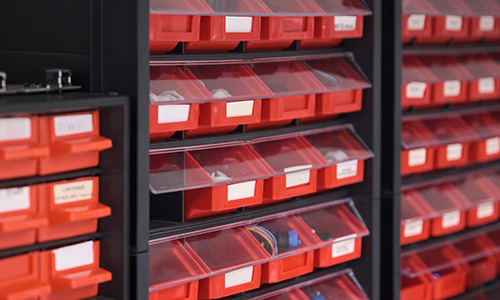 Screws, nuts, bolts, nails and other materials in red storage boxes.