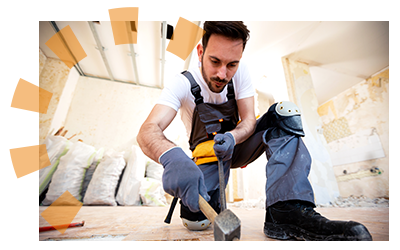 Young man using a pry bar and mallet to carefully remove wood panels and reveal subflooring.