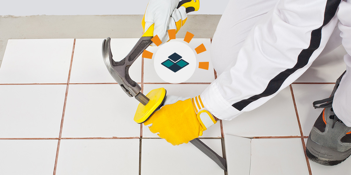 Diyer with gloves hammering chisel to remove ceramic tile.