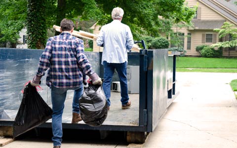 Two Men Filling a Roll Off Dumpster.