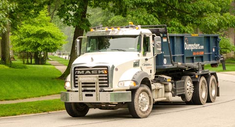 Truck Driving Down Street with Roll Off Dumpster.