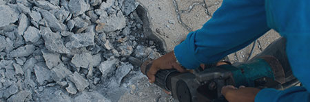 worker breaking up concrete with a jackhammer