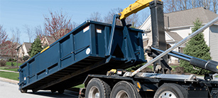 A Roll Off Dumpster is Placed on the Ground by a Truck.