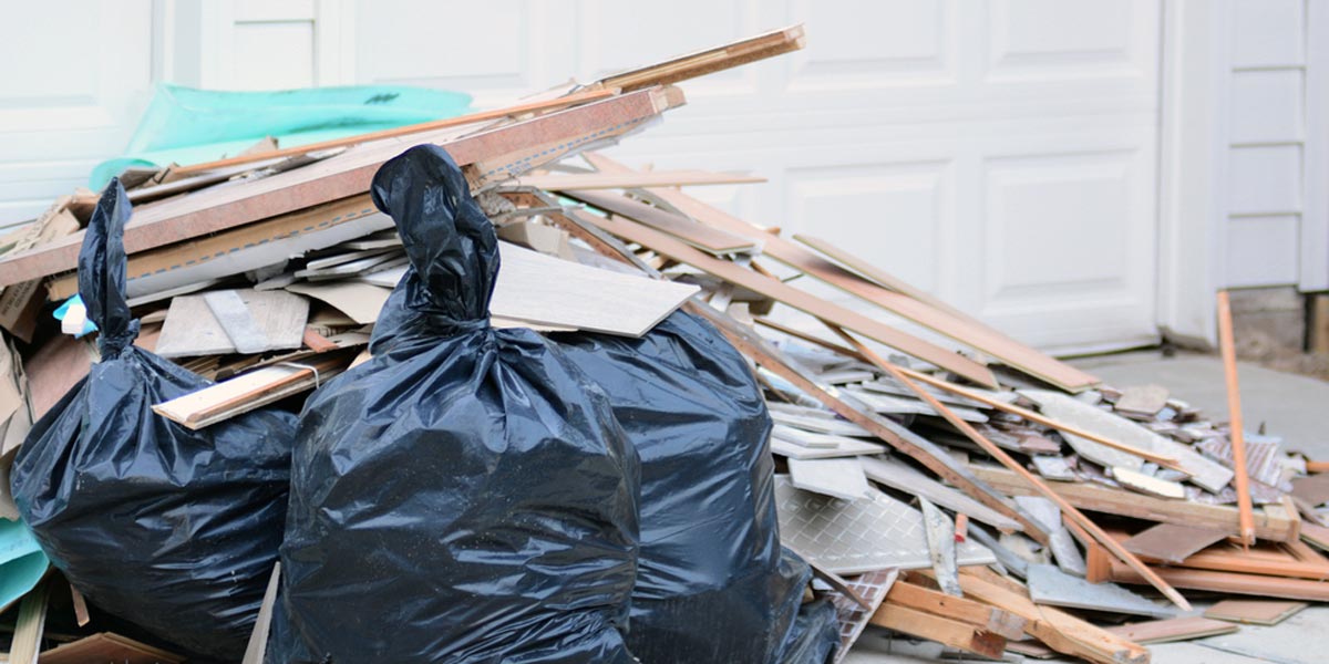 Mixed waste debris in a pile in front of a garage