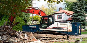 equipment tearing down building surrounded by rubble