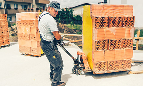 A man pulling construction materials on a dolly.