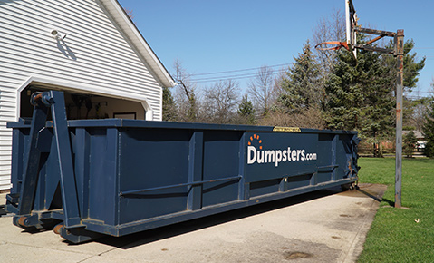 A house with a roll off dumpster in the driveway. 