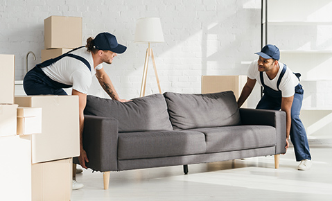 Workers lifting a gray couch.