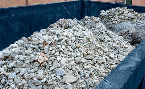 A roll off dumpster with rock and gravel.