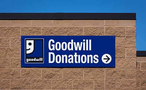 A blue sign on a cinder block building with white words stating Goodwill Donations.