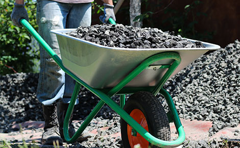 Junk remover moving a pile of rock with a wheelbarrow.